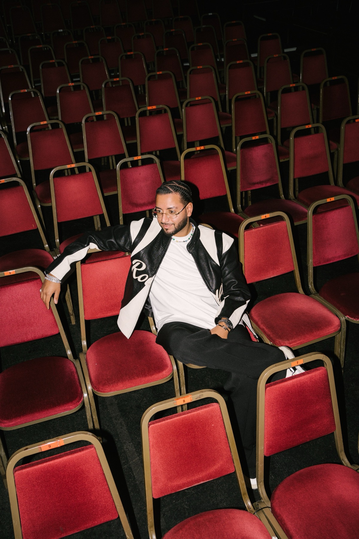 Joey Malik, Host von Joey's Comedy Club, sitzt in einer Reihe roter Theatersessel